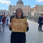 Artista ucraina in via della conciliazione con un cartello: speranza per la pace e papa francesco